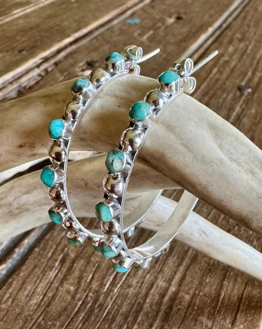 Earrings with turquoise stones on a wooden surface