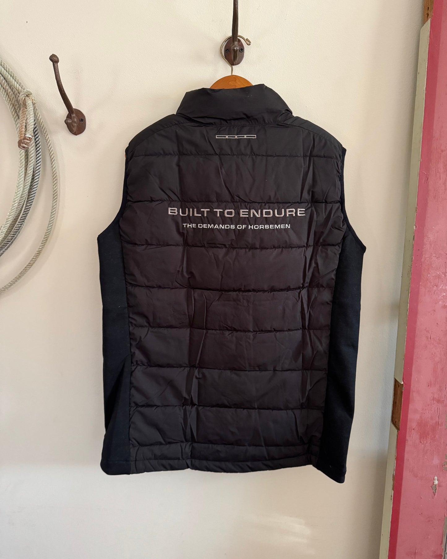 Black puffer vest with text on a white wall