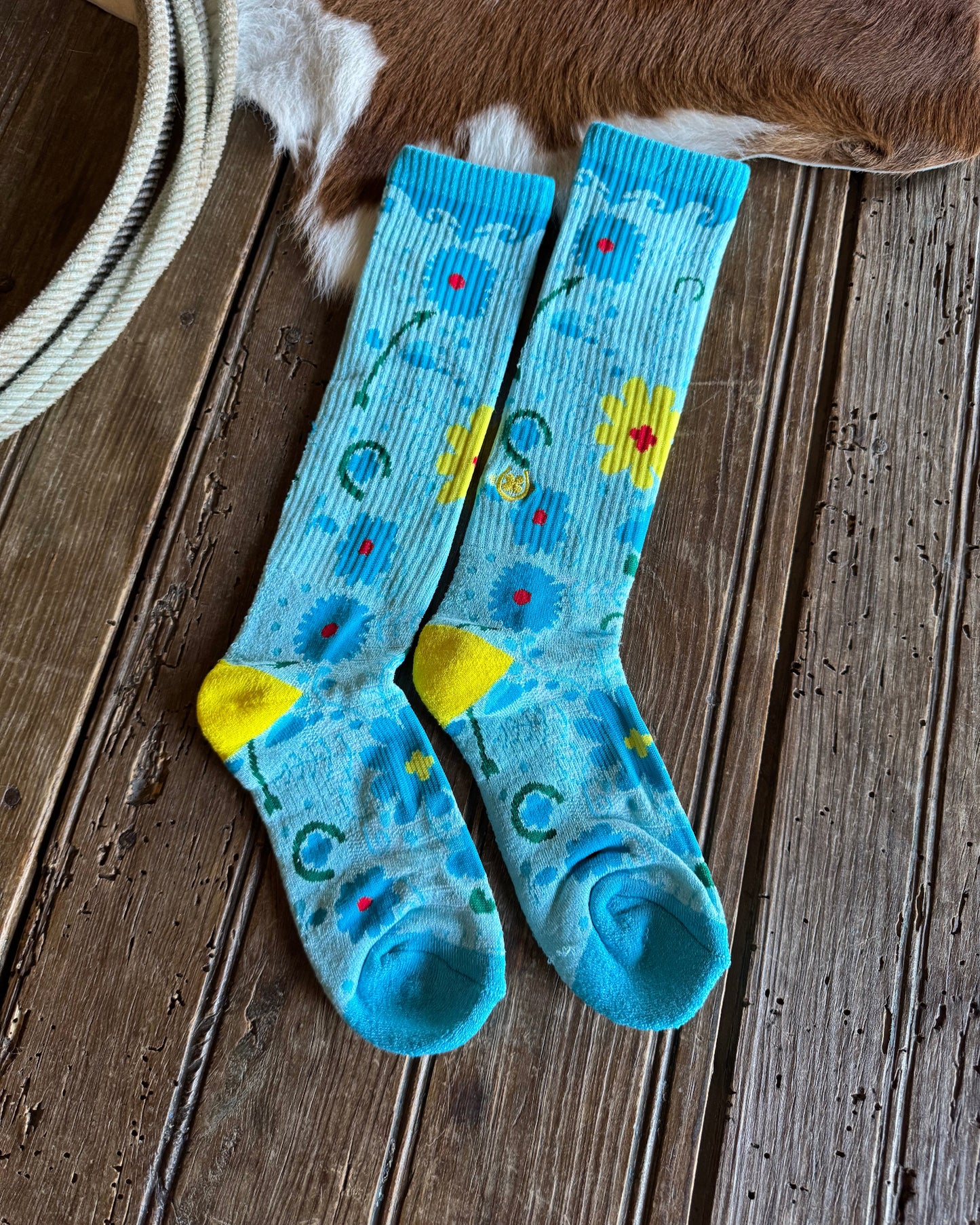 Pair of blue socks with floral patterns on a wooden floor.