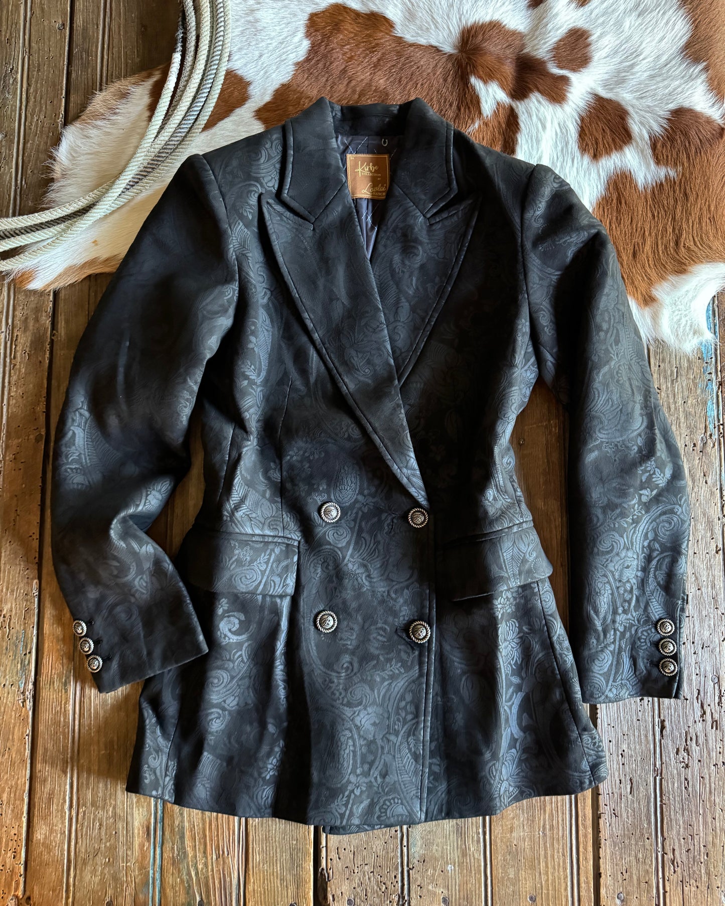 Dark jacket on a wooden surface with a cowhide rug in the background