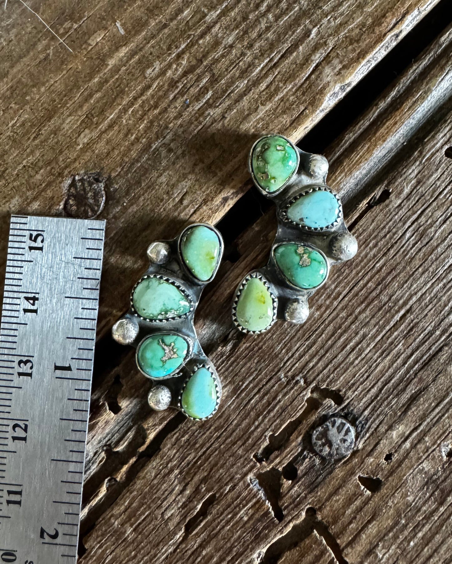 Turquoise stone jewelry piece on a wooden surface with a ruler for scale.