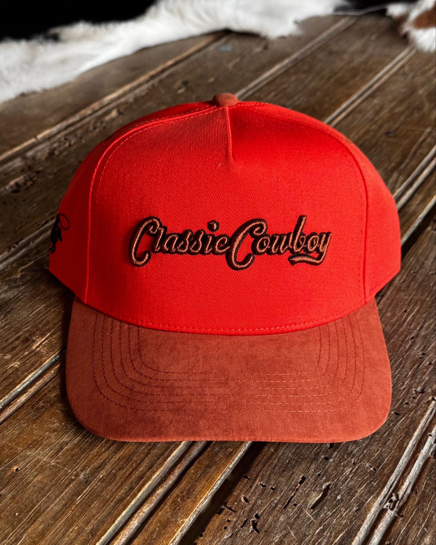 Orange cap with 'Classic Cowboy' logo on a wooden surface