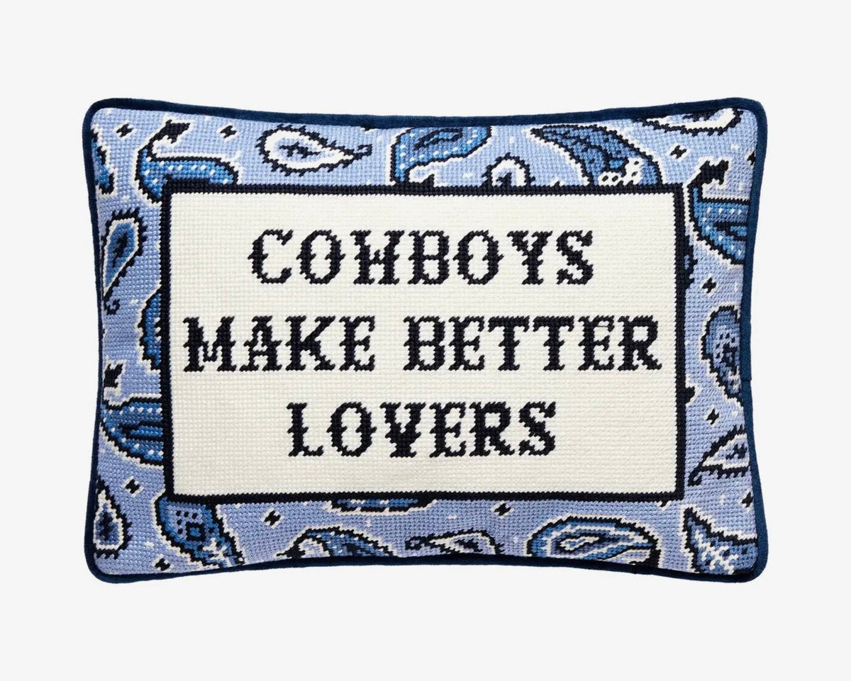 Decorative pillow with text 'Cowboys Make Better Lovers' on a blue patterned background