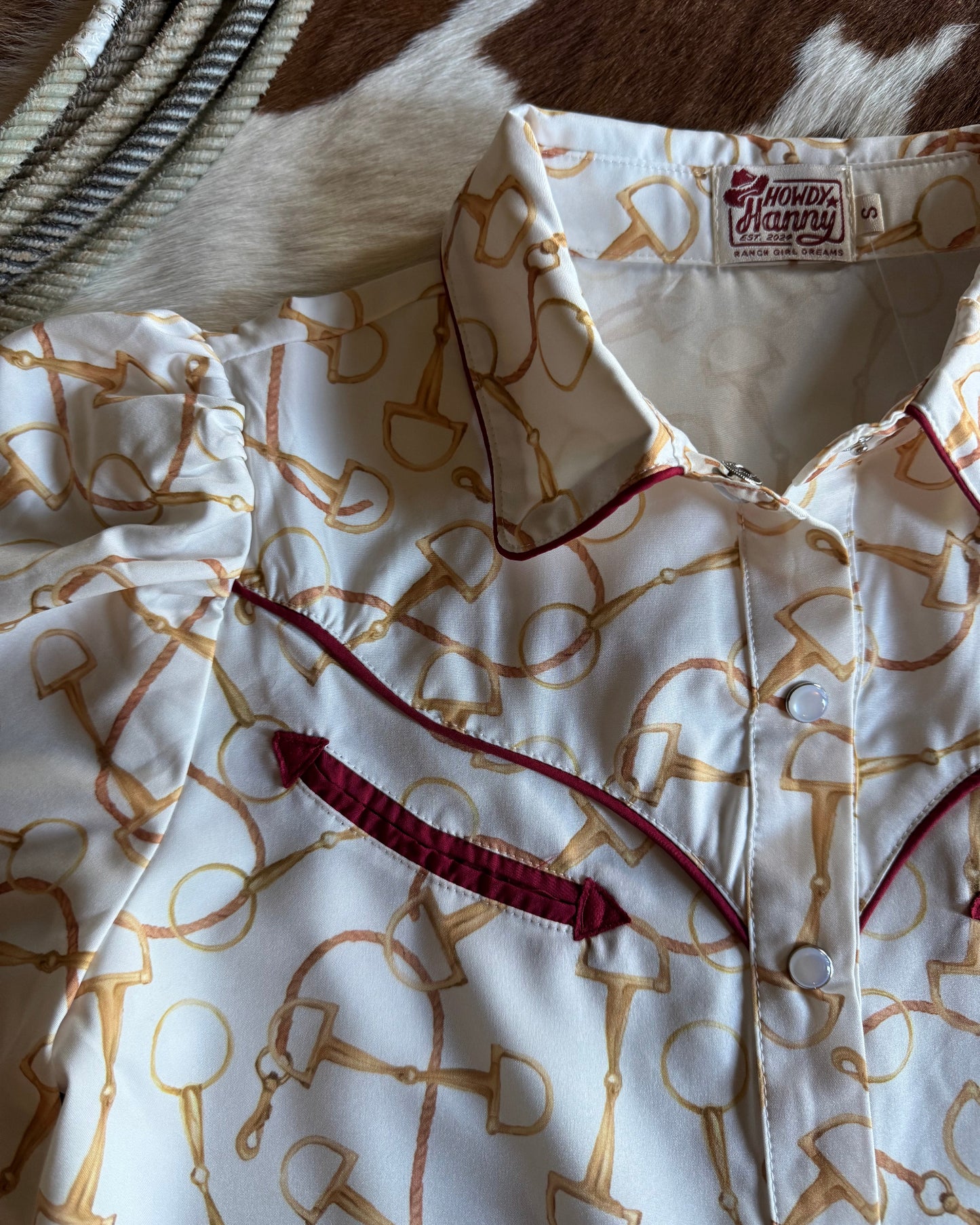 Close-up of a shirt with a pattern and brand label, partially on a cowhide surface.
