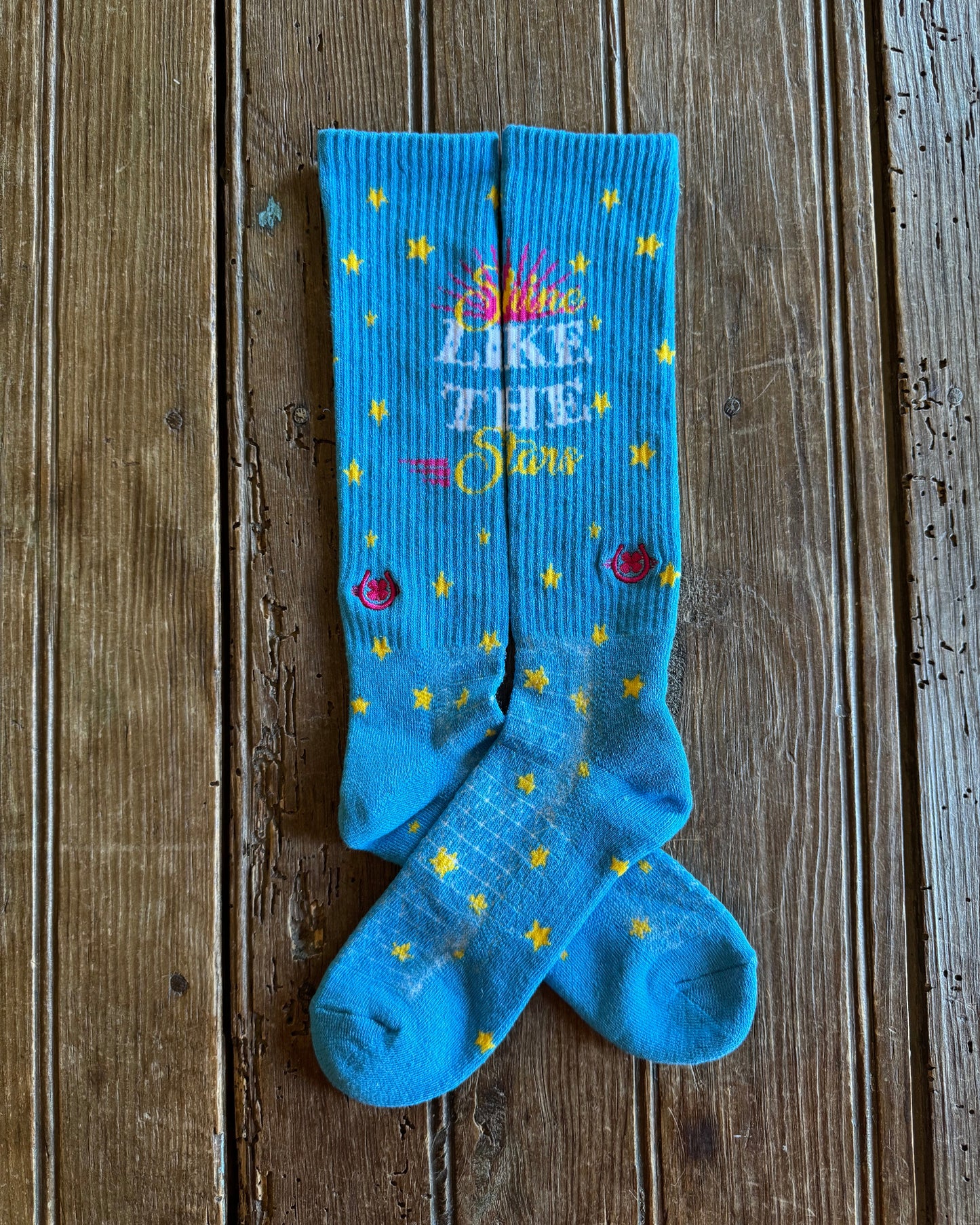 Shine Like a Star Performance Socks in turquoise showing design on rustic wood background