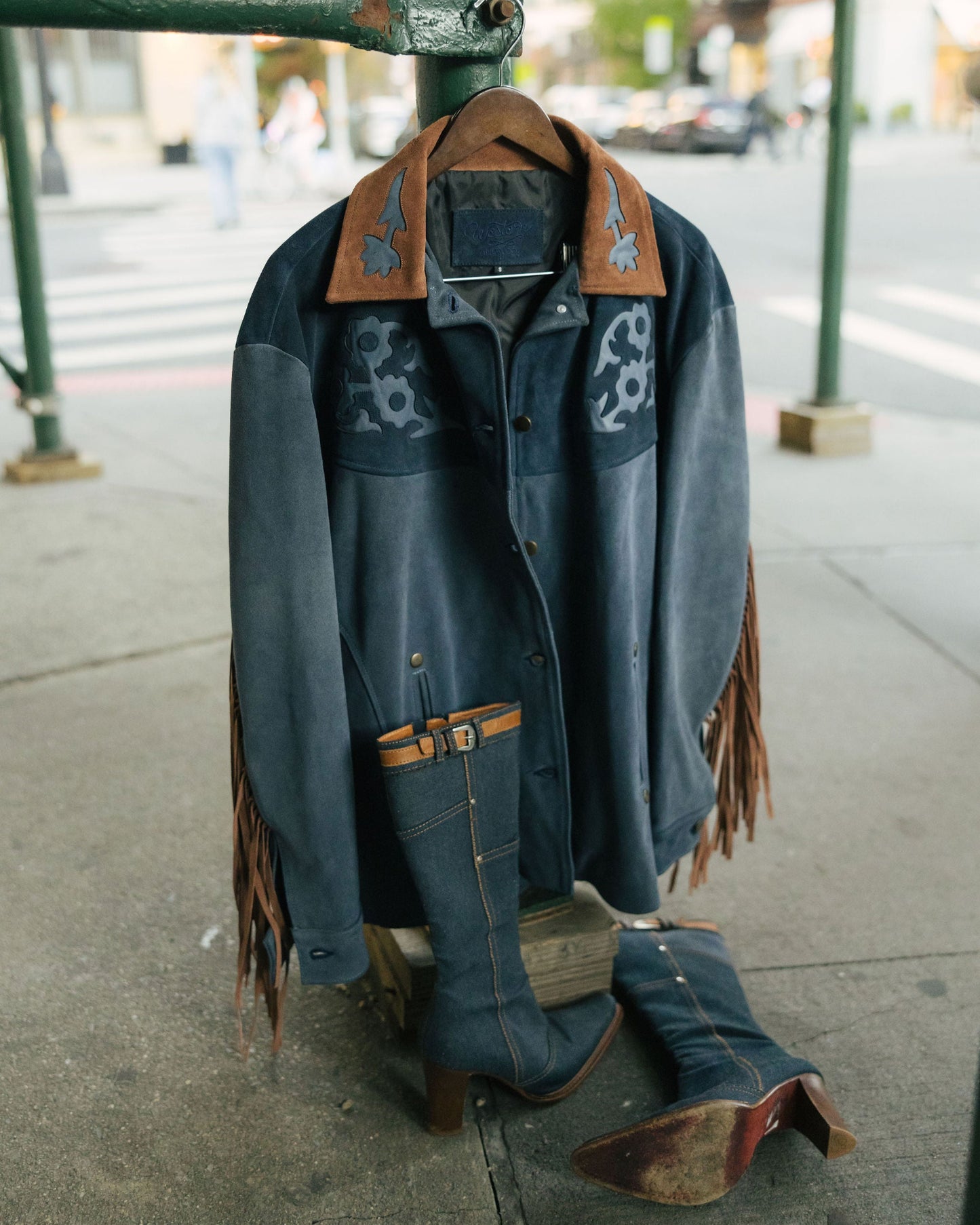 Blue denim jacket with brown leather accents on a mannequin outdoors.
