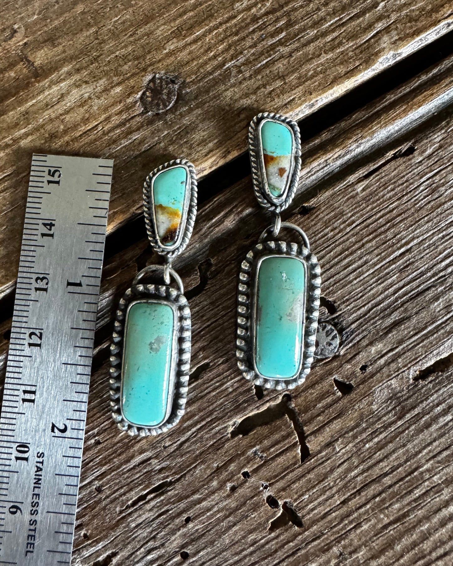 turquoise drop earrings on a wooden surface with a ruler for scale