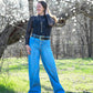Model standing in wooded area wearing fashionable outfit with high waisted wide leg jeans 