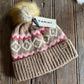 Knitted beanie with patterned front and pom-pom on a wooden surface, Ariat brand tag visible