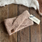 Beige knitted headband with Ariat tag on a wooden surface