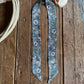 sage green ribbon scarf with turquoise concho pattern on a wooden surface