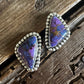 Purple stone earrings with silver setting on a wooden surface