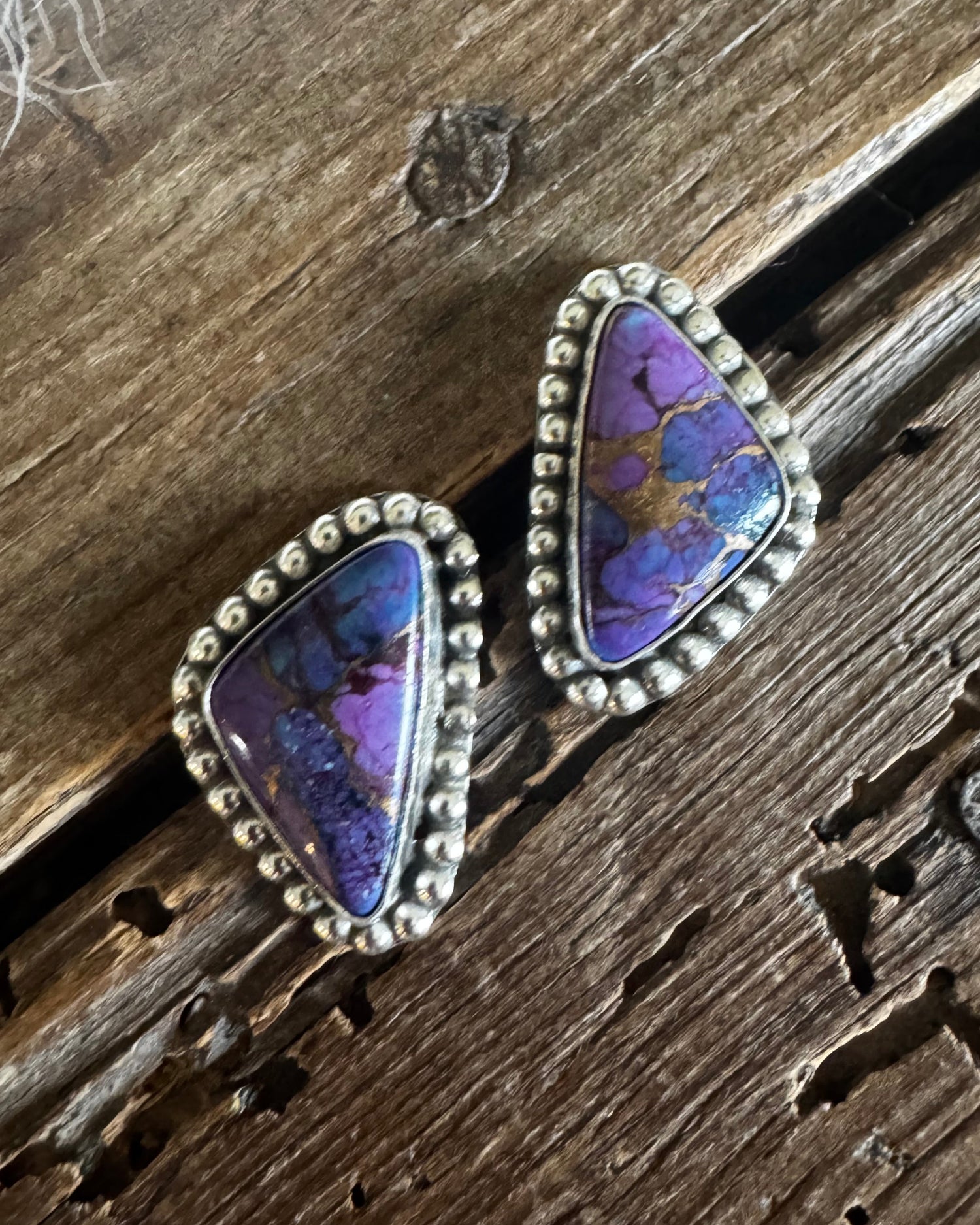 Purple stone earrings with silver setting on a wooden surface