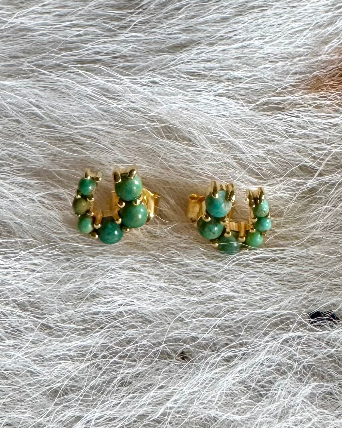 Turquoise and gold horseshoe earrings on a cowhide 
