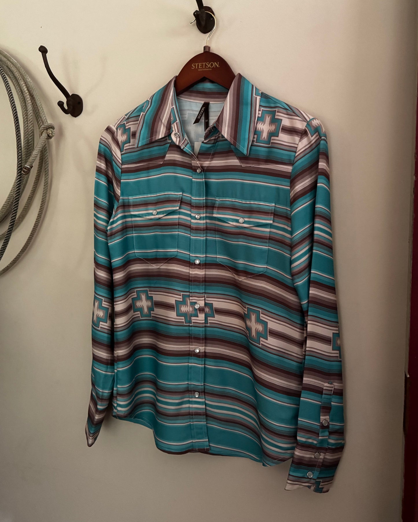 Striped shirt with geometric pattern hanging on a hook against a white wall