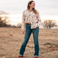 Model standing in a field, dressed in a stylish modern western outfit.