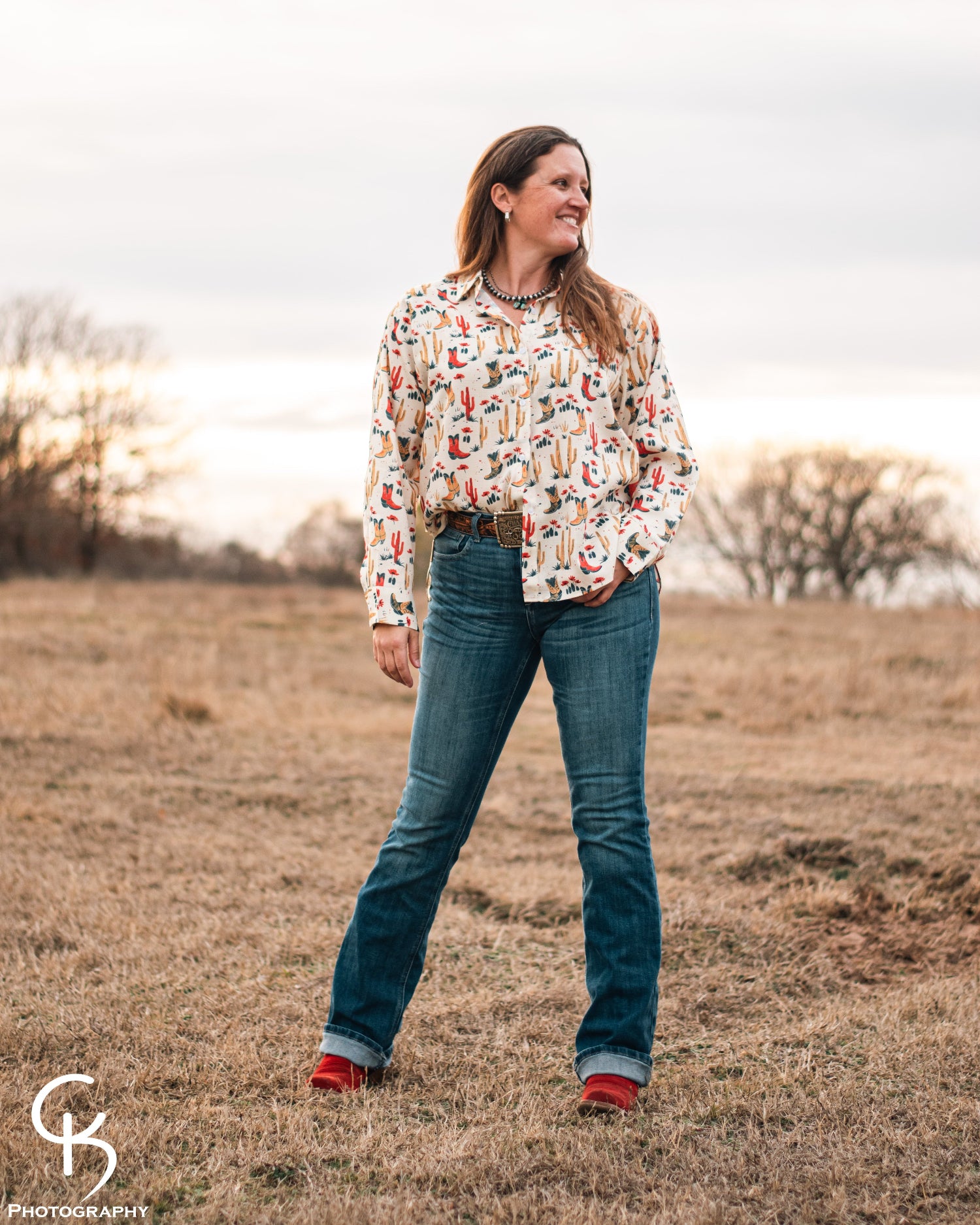 Model standing in a field, dressed in a stylish modern western outfit.