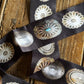 Decorative buttons with intricate designs on a dark ribbon against a wooden background
