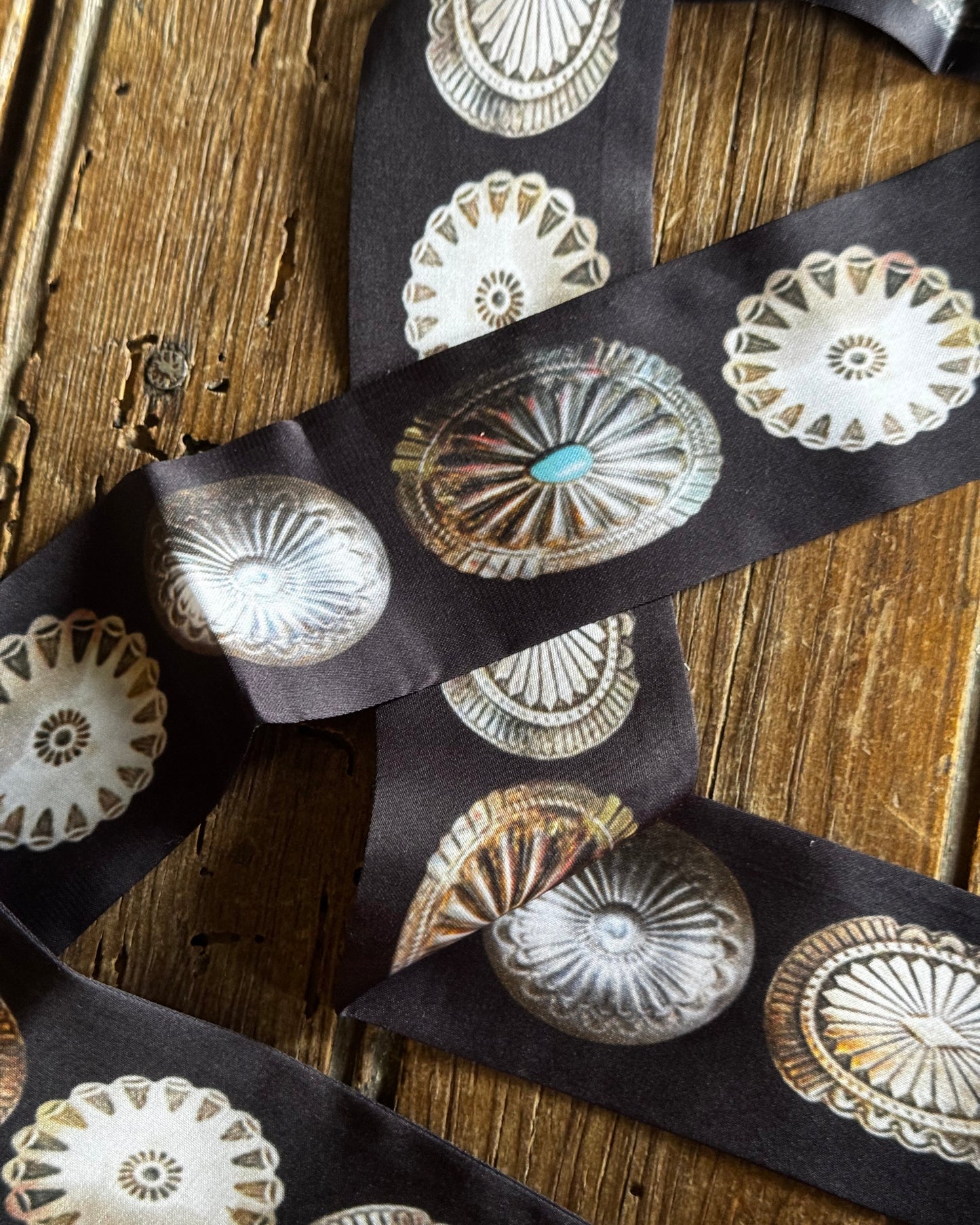 Decorative buttons with intricate designs on a dark ribbon against a wooden background
