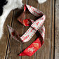 Red and white patterned scarf on a wooden surface with fur in the background