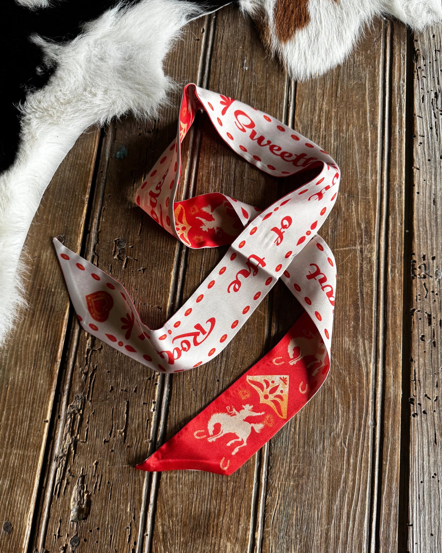 Red and white patterned scarf on a wooden surface with fur in the background