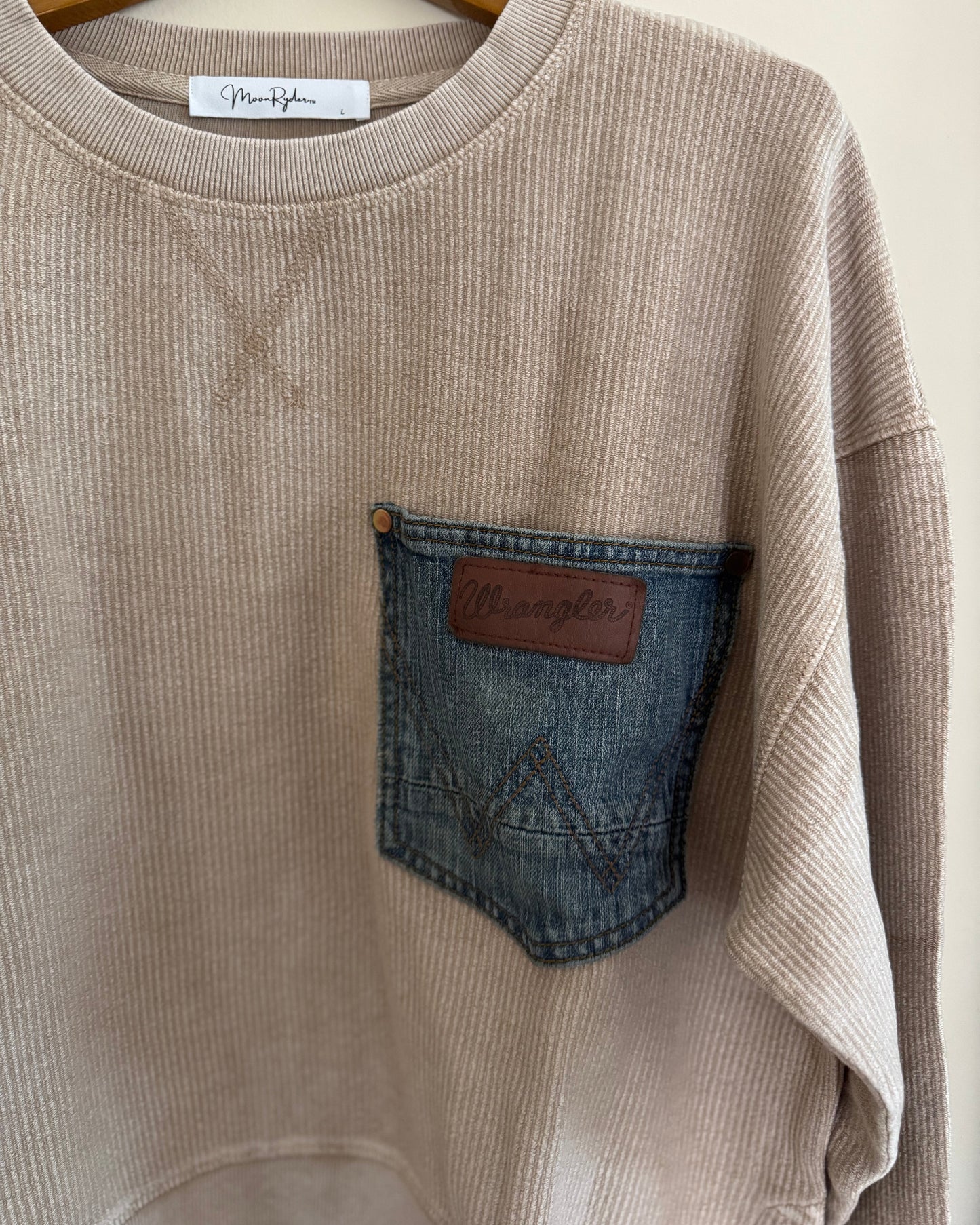 Beige sweatshirt with denim pocket on a hanger