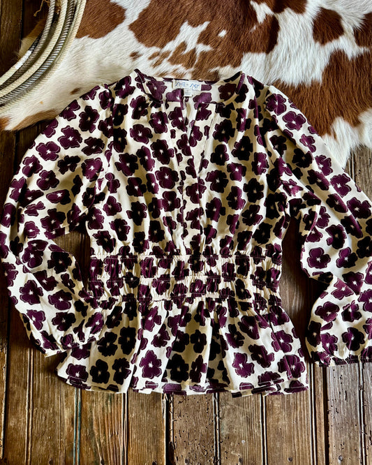 Floral print top on a wooden surface with a cowhide rug in the background