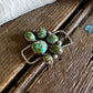 twilly slide with green gemstones on a wooden surface