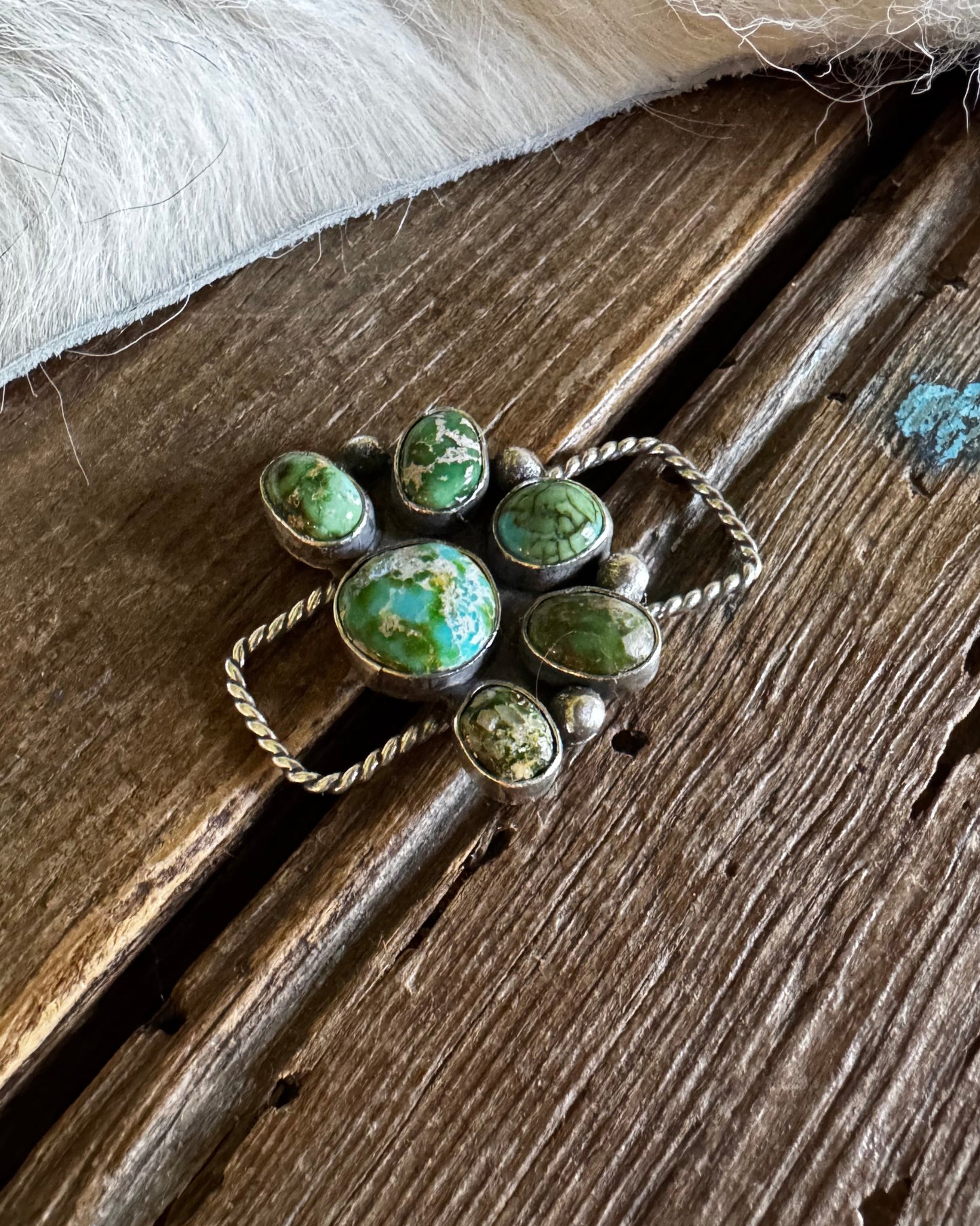 twilly slide with green gemstones on a wooden surface
