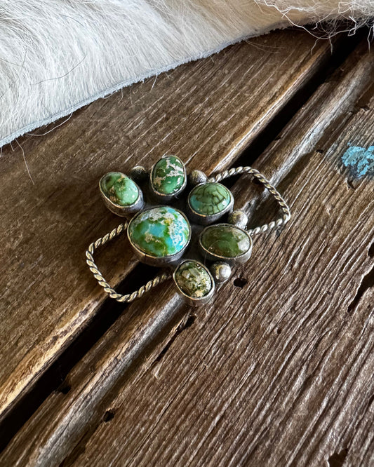 twilly slide with green gemstones on a wooden surface