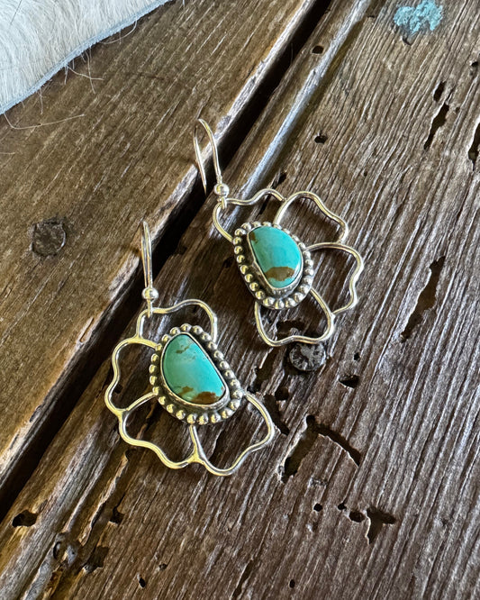 Silver earrings with turquoise stones on a wooden surface
