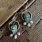 Silver earrings with green and pink stones on a wooden surface