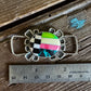 Colorful brooch on a wooden surface with a ruler for scale
