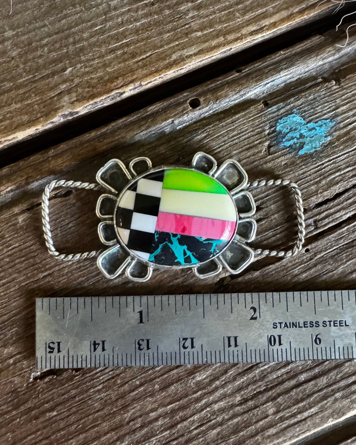 Colorful brooch on a wooden surface with a ruler for scale