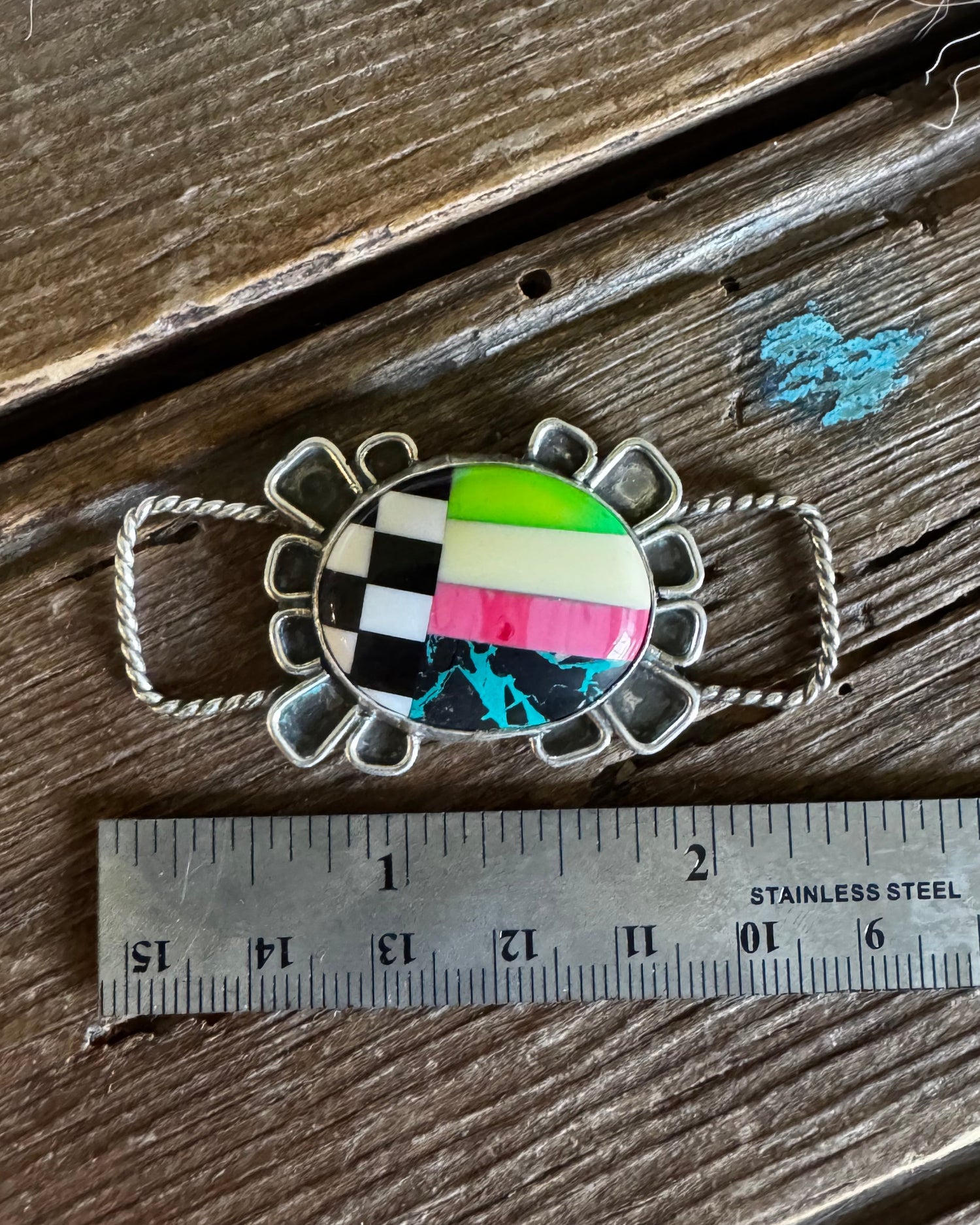 Colorful brooch on a wooden surface with a ruler for scale