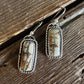 Pair of silver earrings with stone-like inserts on a wooden surface