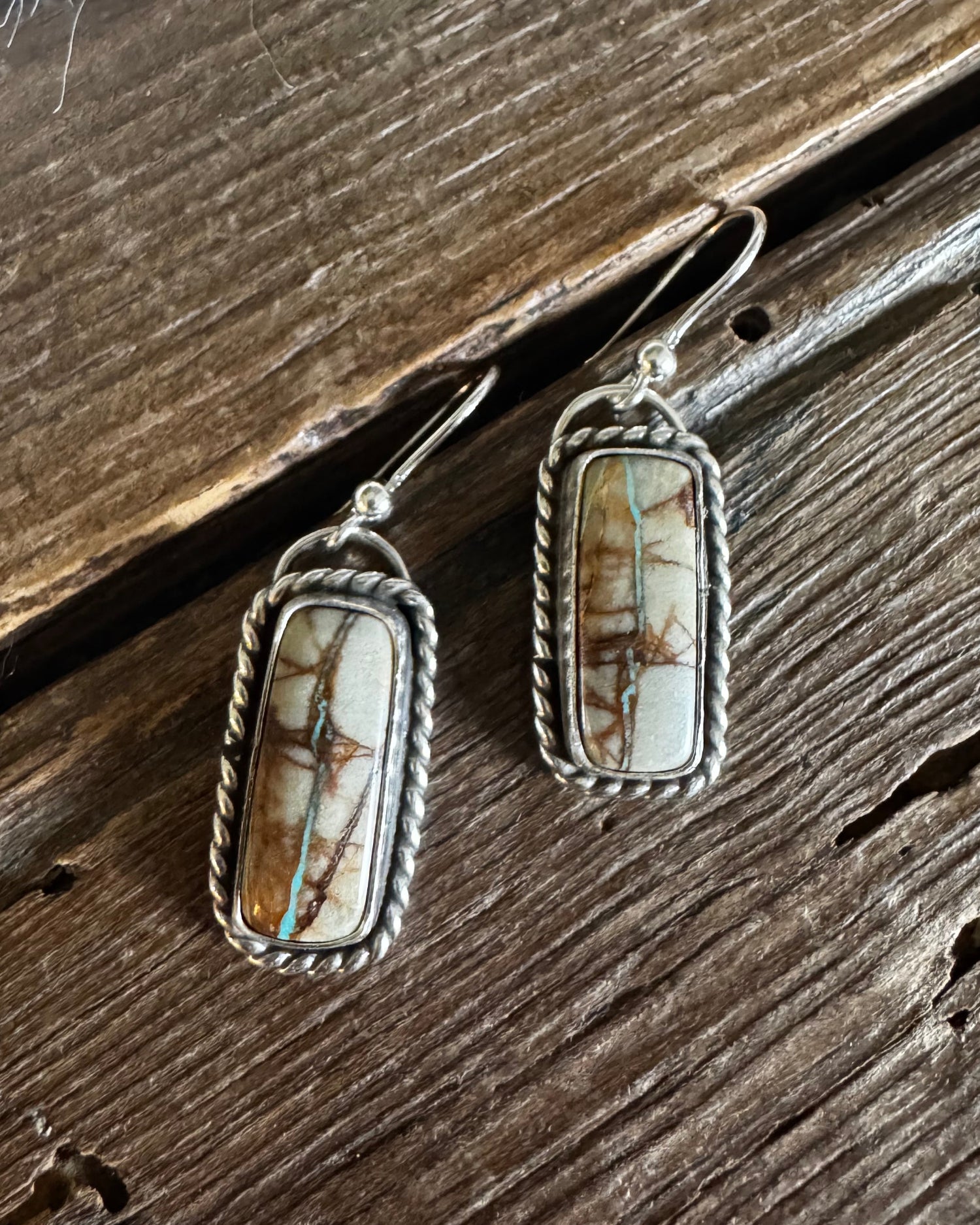 Pair of silver earrings with stone-like inserts on a wooden surface