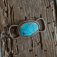 Turquoise stone twilly slide with silver band on a wooden surface