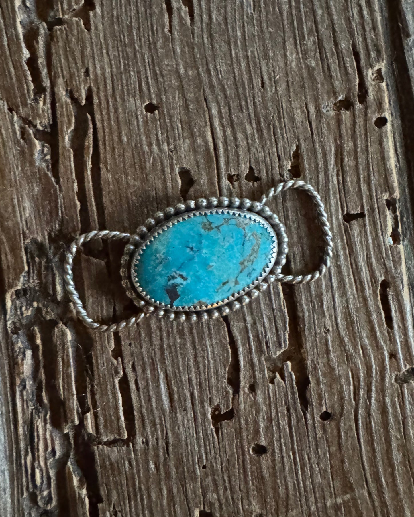 Turquoise stone twilly slide with silver band on a wooden surface