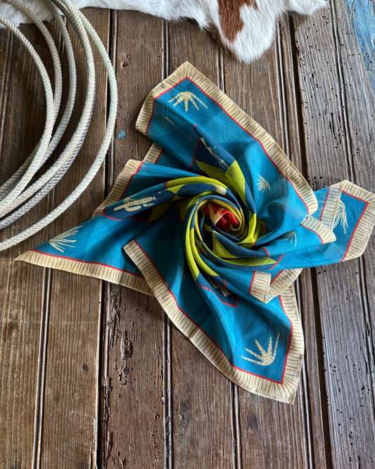 Blue patterned fabric on a wooden surface with a cowhide rug and rope.