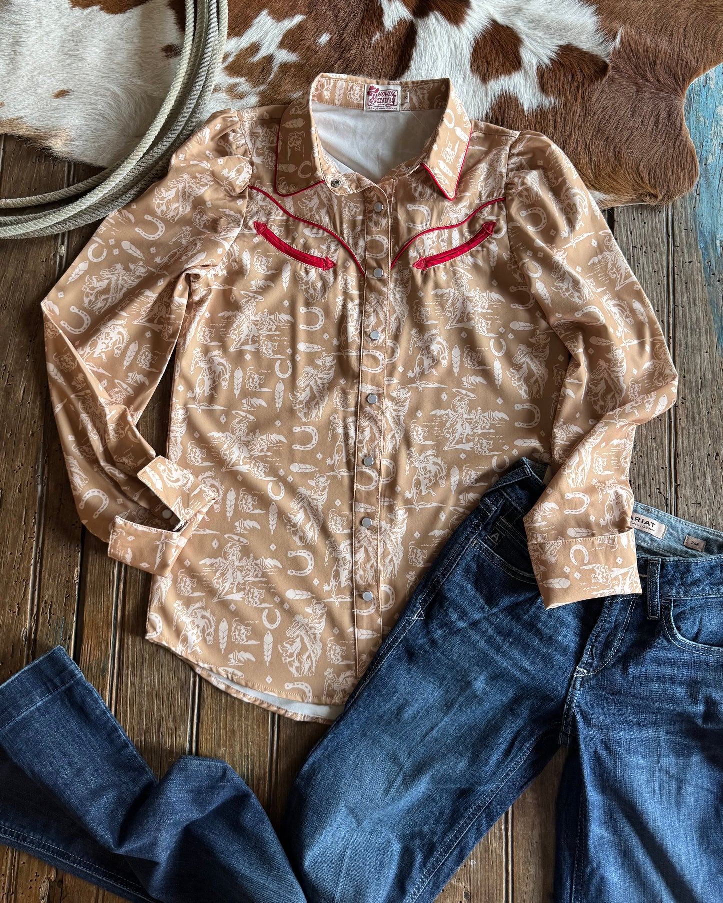Beige shirt with text, blue jeans, and cowhide rug on a wooden surface