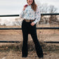 Model standing by a pipe fence in a field, dressed in a stylish modern western outfit.