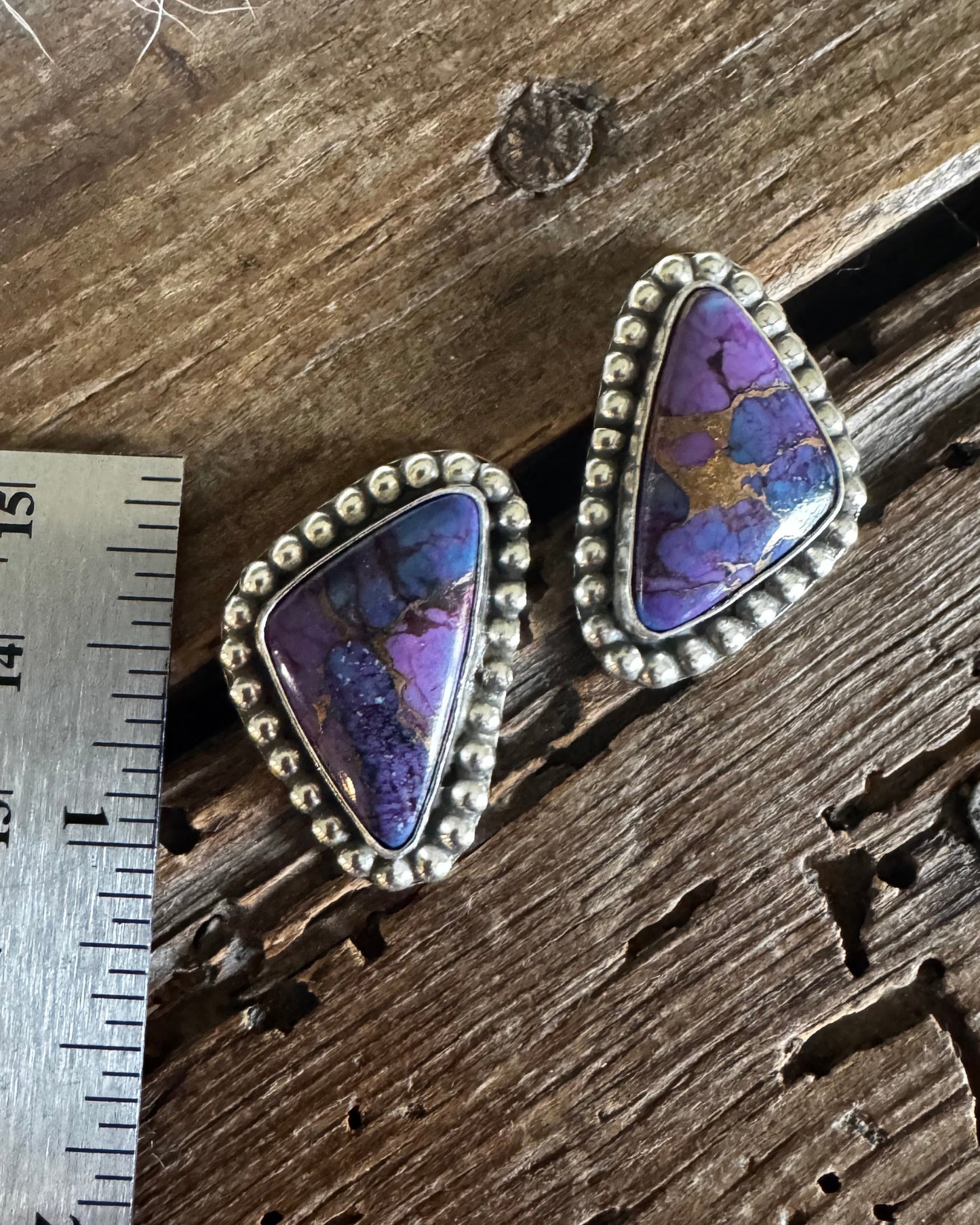 Pair of purple gemstone earrings on a wooden surface with a ruler for scale.