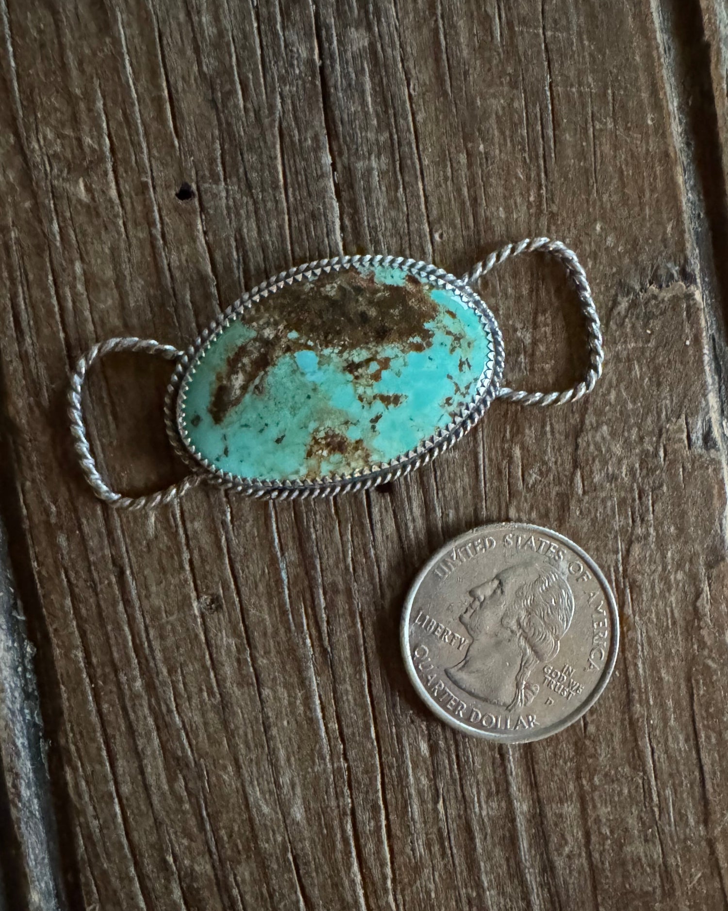 Turquoise stone twilly slide on a wooden surface with a coin for scale