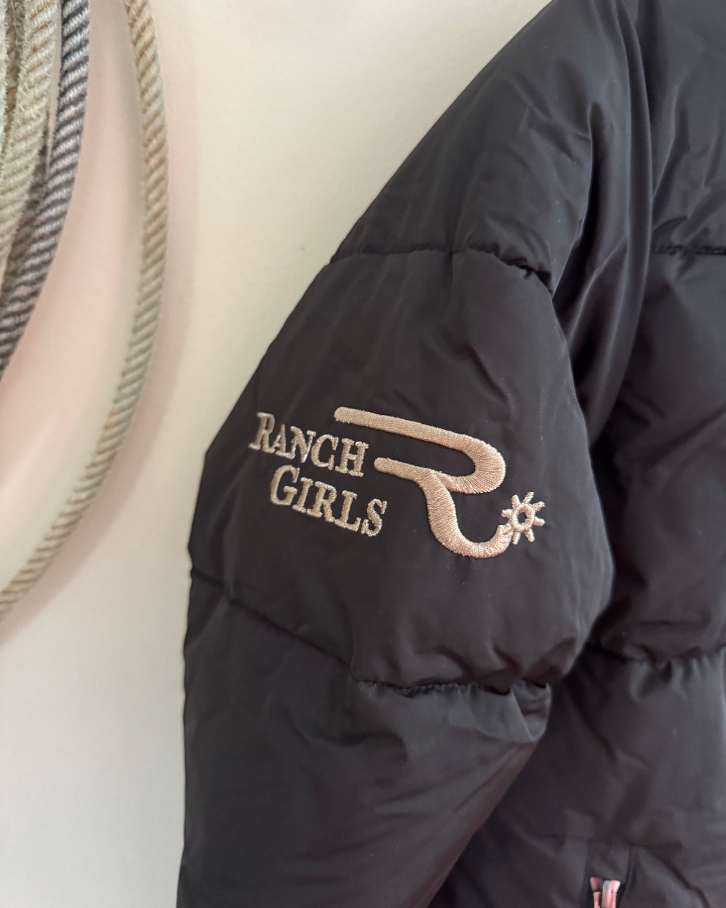 Black puffer jacket with 'Ranch Girls' logo on a white background