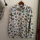 Floral patterned shirt hanging on a wooden hanger against a white wall.