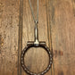 Metal snaffle bit with chain on a wooden surface