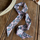 Pink and turquoise patterned ribbon scarf on a wooden surface