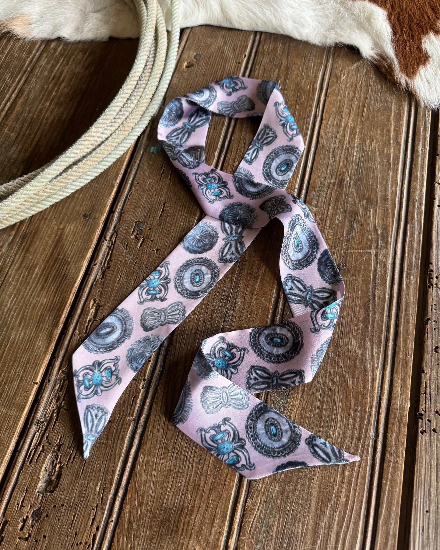 Pink and turquoise patterned ribbon scarf on a wooden surface