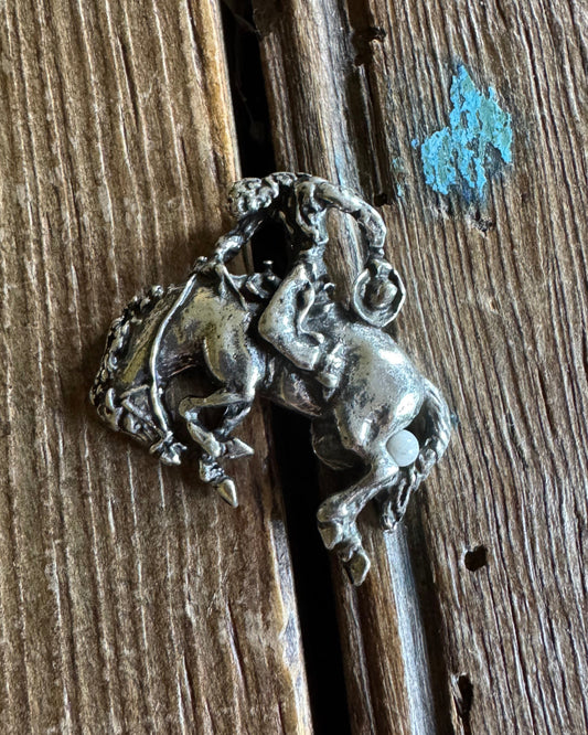 Silver bronc rider pin on wooden background 